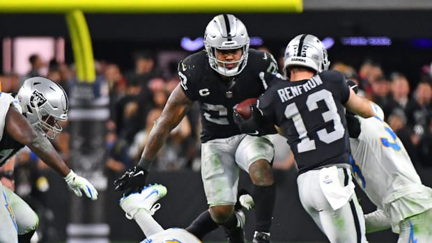 Las Vegas Raiders running back Josh Jacobs (28) hurdles the tackle attempt of Los Angeles Chargers defensive end Joey Bosa (97) during an overtime period at Allegiant Stadium.